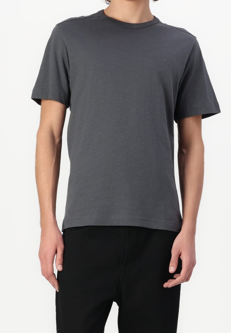 T-shirt gris à col rond fabriqué en tissu doux avec des manches courtes. Présente un logo discret sur la poitrine et une coupe décontractée.