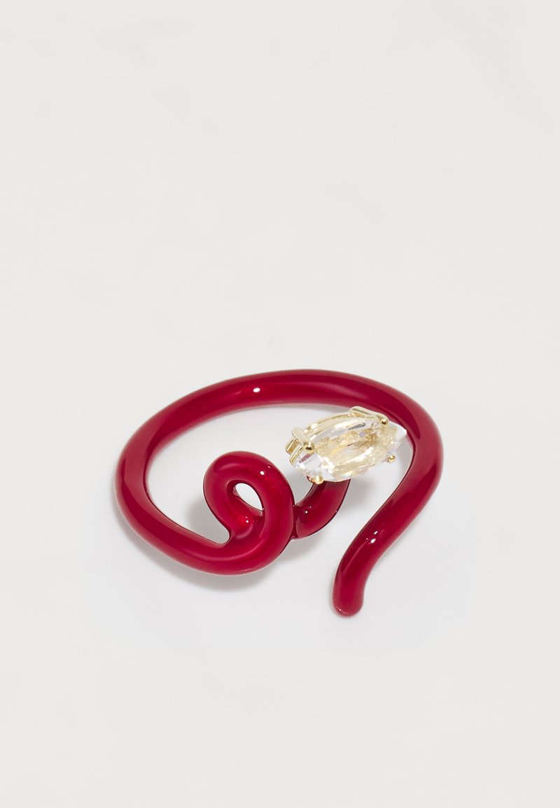 Roter gedrehter Harzring mit einem facettierten klaren Stein, der in goldfarbigen Beschlägen eingefasst ist. Glatte Oberfläche mit spiralisiertem Design.