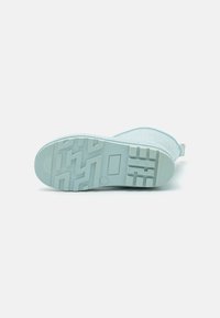 Scarpa slip-on di un blu chiaro, con una superficie testurizzata e una robusta suola in gomma caratterizzata da un motivo a zigzag e un'apertura sul tallone per facilitare indossarlo.