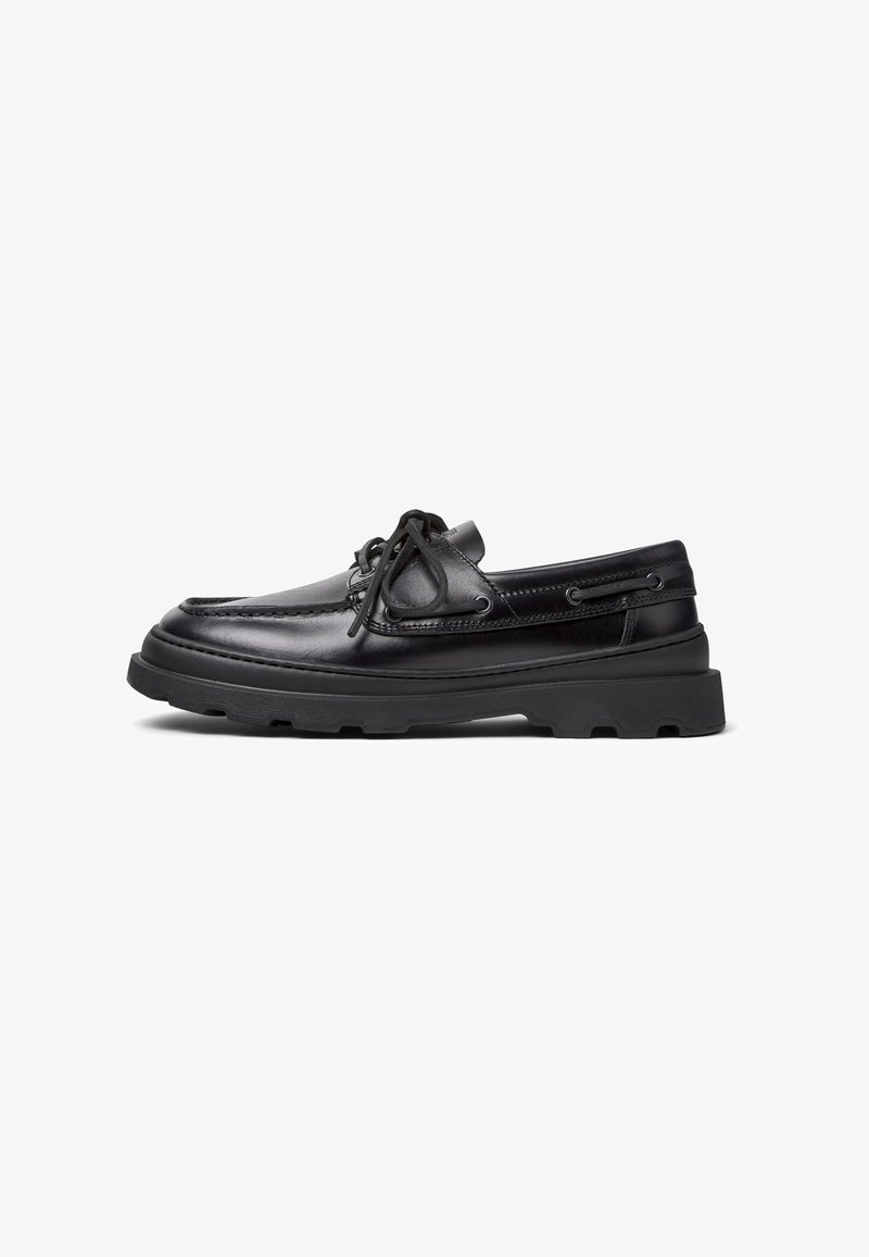 Zwarte leren bootsschouders met een ronde neus, twee vetergaatjes en contrasterende stiksels; rubberen zool met gestructureerde profiel voor grip.