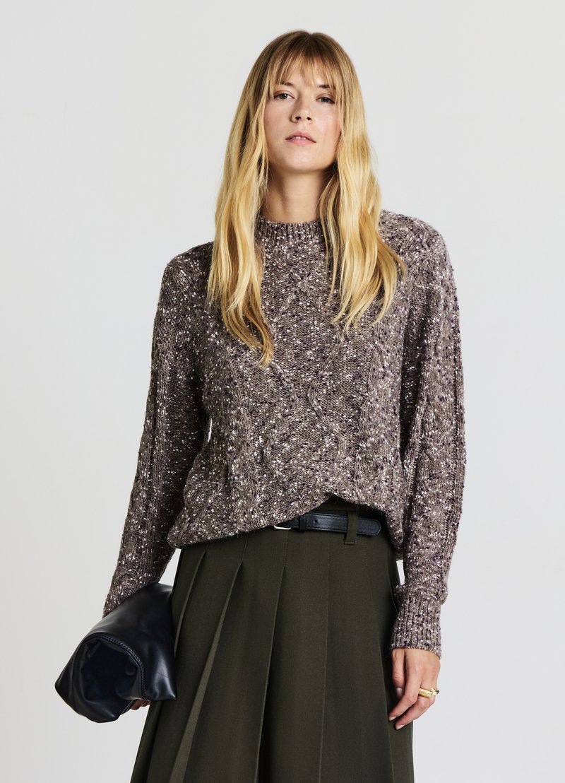 Knit sweater in gray with speckled white accents, round neck, and loose fit. Paired with a dark green pleated skirt and leather clutch.