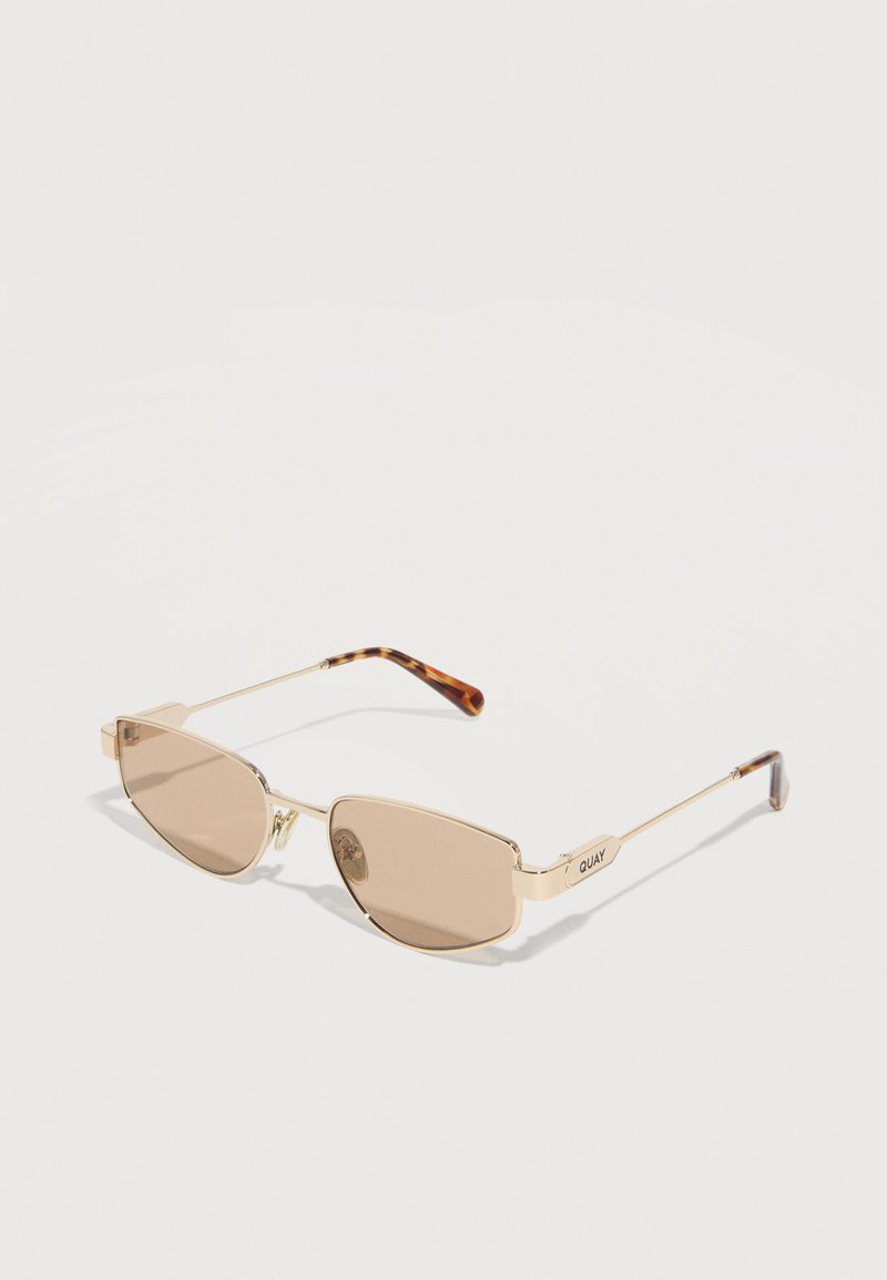 Χρυσά ορθογώνια γυαλιά ηλίου με καφέ σκουρόχρωμους φακούς και ναυτίλια κέρατα με σχέδιο χελώνας, τοποθετημένα σε γωνία πάνω σε λευκή επιφάνεια.