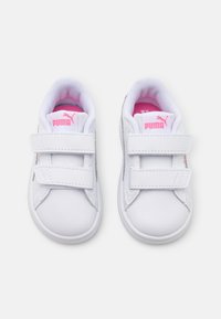 Scarpe da ginnastica bianche per bambini in materiale sintetico, con dettagli rosa, punta tonda, due cinturini in Velcro e colletto imbottito.