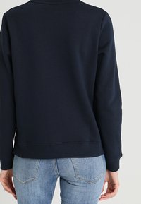 Felpa blu navy con collo e polsini a coste, caratterizzata da una vestibilità comoda e una superficie in cotone morbido. Design semplice, senza motivi né accenti.