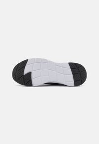 Semelle de chaussure de sport en noir et blanc, présentant des motifs de grip texturés, un design de semelle rectangulaire et une apparence légère.