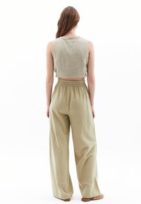 Lichtgroen cropped tanktop van textuur stof, gecombineerd met losse, hoge taille, wijde broek, beide gemaakt van zachte, ademende materialen.
