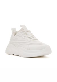 Witte sport sneakers met een getextureerde mesh bovenkant, dikke tussenzool en een opvallend vetersysteem. Voorzien van een trekhaak voor eenvoudig aan- en uittrekken.