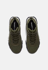 Zielone oliwkowe sneakersy z perforowaną teksturą, szare sznurowadła, wzmocniony czubek i solidna czarna podeszwa. Logo Timberland na wkładce.