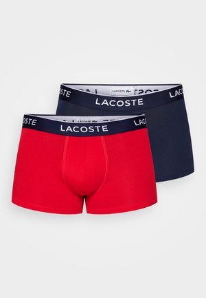 Boxer aderenti rossi e blu navy con cintura elastica che presenta il logo Lacoste. Realizzati in tessuto morbido, progettati per comfort e vestibilità.