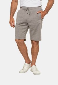 Shorts en coton gris avec une taille élastique et un cordon de serrage, dotés de poches latérales et d'une coupe décontractée, accompagnés de baskets blanches.