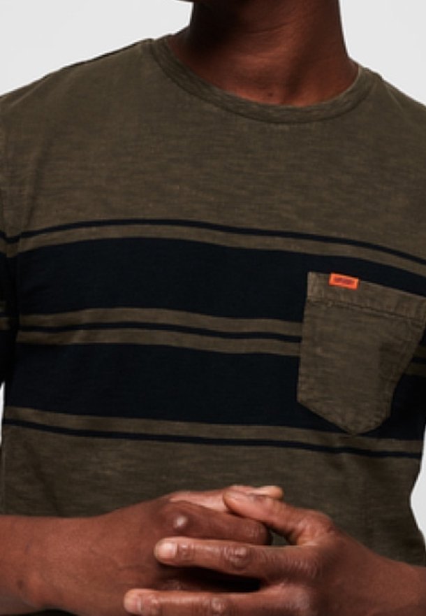 T-shirt à rayures vert olive et noir avec une finition texturée, présentant une poche sur la poitrine gauche et un petit détail de marque orange.