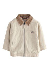 Bézs dzseki barna kordbársony gallérral, elülső cipzárral és rugalmas szegéllyel. Oldalzsebekkel és a mellkason egy kis logóval rendelkezik.