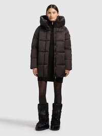 Svart dunjacka med stor huva och quiltad design, kombinerad med en svart stickad klänning och svarta stövlar med texturerad yta.