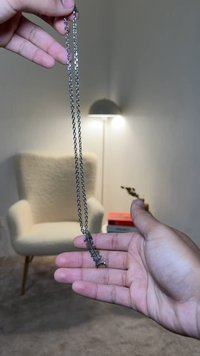 Silberne Kettenhalskette mit einem Fischgrätenanhänger. Die Kette ist mit ovalen Gliedern strukturiert und zeigt ein detailliertes Fischgrätendesign.