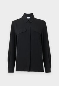 Μαύρη μπλούζα με κουμπιά, κατασκευασμένη από ελαφρύ ύφασμα, με μυτερό γιακά, μακριά μανίκια και δύο τσέπες στο στήθος με καπ άκια.