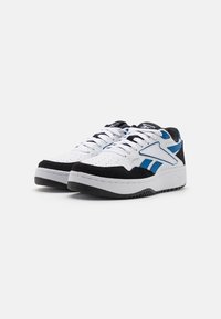 Baskets blanches et noires avec accents bleus ; matériaux en cuir et en daim ; embout perforé en blanc ; semelle intermédiaire blanche épaisse ; semelle extérieure en caoutchouc noir.