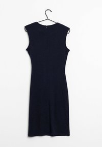 En mörk marinblå ärmlös klänning hänger på en svart krok mot en vit bakgrund, som visar en enkel, figursydd design.