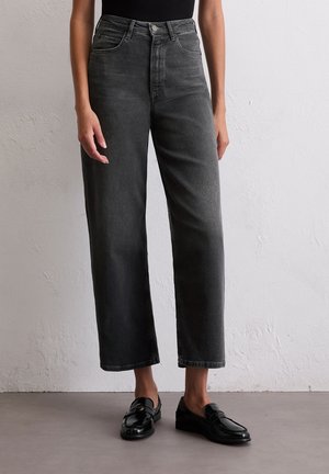 Hoge taille grijze denim jeans met een rechte pasvorm, voorzien van vijf zakken en subtiele vervaging. Gecombineerd met zwarte instapschoenen.