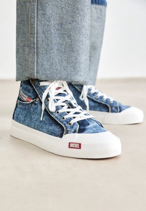 Denim high-top sneakers with white laces, featuring a thick white sole and a red Diesel logo on the side. Light blue distressed denim texture.