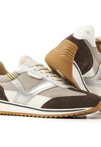 Sneakers with a beige mesh upper, brown suede accents, silver metallic details, and a textured gum rubber sole; features a plush collar.