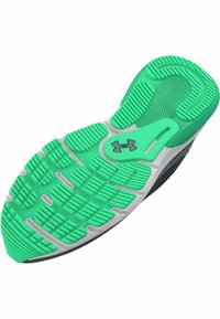 Suela de goma verde con patrones de agarre texturizados, acentos en blanco y gris oscuro, y un diseño moldeado para una mejor tracción. Logo de Under Armour presente.