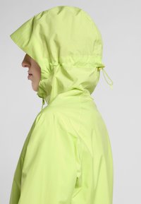 Leichte, kapuzenjacke in leuchtendem Neon-Gelb, mit verstellbaren Kordeln und glatter Textur, entworfen für den Einsatz im Freien.