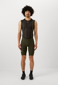 Olijfgroene fiets bretels met een zwarte mesh bovenkant, voorzien van verstelbare banden en een gewatteerde zit, ontworpen voor comfort en prestaties.
