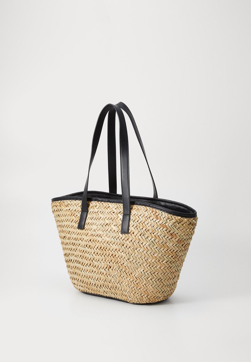 Sac en osier tissé avec poignées en cuir synthétique noir, présentant une forme structurée et un liseré noir lisse le long du bord supérieur.
