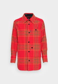 Rød ternet skjorte med sort og orange check mønster, featuring en brystlomme og sorte knapper; blød stofstruktur.