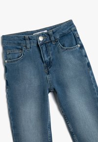 Jeans i medelblått med blekt utseende, fem fickor, knappstängning fram och kontrasterande gult stygn.