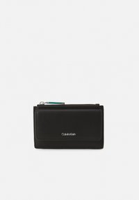 Portefeuille en cuir noir avec une texture lisse, doté d'une fermeture éclair et d'un petit logo argenté à l'avant. Forme rectangulaire compacte.