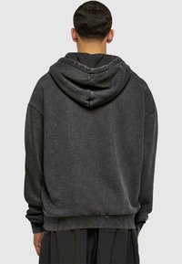 Dark gray hooded sweatshirt with a relaxed fit, textured fabric, ribbed cuffs and hem, featuring a large hood and no visible branding.