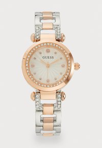 Montre ronde avec un bracelet en métal argent et or rose. Cadran blanc texturé orné d'accents en or rose et de détails en cristal.