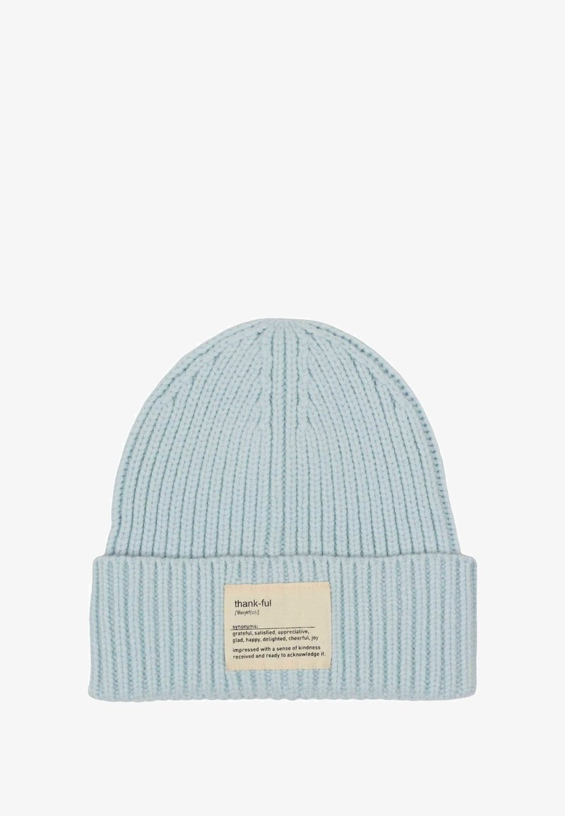 Light blue knitted beanie with ribbed texture and a folded cuff. Features a rectangular fabric label with "thank-ful" and definition.