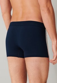 Calzoncillos ajustados de color azul marino con una cinturilla suave, costuras detalladas y una franja lateral en contraste. Fabricados en un tejido suave y elástico.