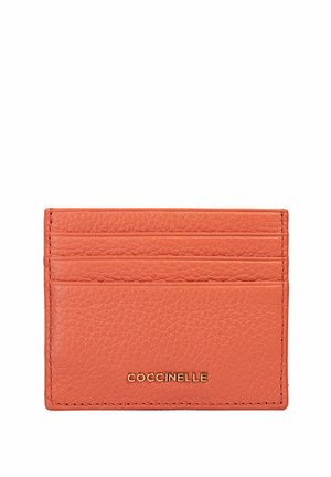 Porte-cartes en cuir orange avec une surface texturée. Dispose de cinq fentes pour cartes et d'un logo doré à l'avant. Design compact et rectangulaire.