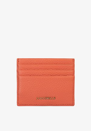 Portafoglio in pelle arancione con superficie texturizzata. Presenta cinque slot per carte e un logo dorato sulla parte anteriore. Design compatto e rettangolare.
