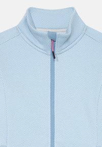 Giacca zip con cappuccio in blu chiaro, realizzata in un tessuto a rete testurizzato, con colletto alto e dettaglio zip rosa a contrasto. Cuciture rinforzate visibili.