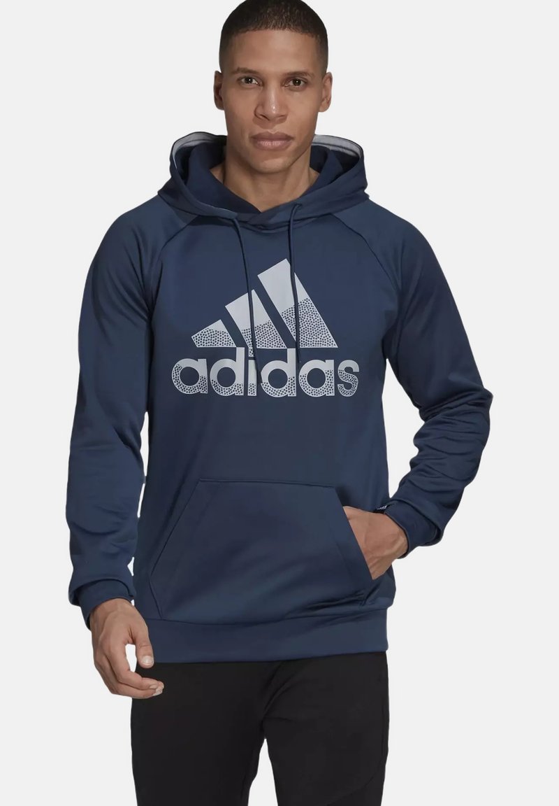 Sudadera azul marino con capucha ajustable, bolsillo canguro y gran logo gris de Adidas en la parte delantera. Tejido suave, mangas largas, corte regular.