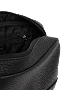Borsa in pelle nera con esterno texturizzato, dotata di apertura con zip. L'interno presenta una fodera con motivo a logo e una piccola tasca con zip.