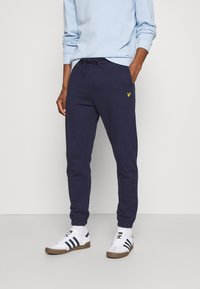 Navy blaue Sweatpants aus Baumwollmischung mit verstellbarem Kordelzugbund und kleinem gelben Logodetail am linken Oberschenkel.