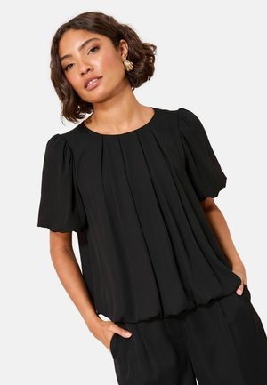 Schwarzes Kurzarmoberteil mit Falten, rundem Halsausschnitt und weicher Drapierung. Leichter Stoff mit glatter Textur. Kombiniert mit passenden Hosen.