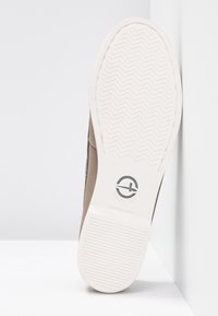 Chaussure marron avec une tige lisse et texturée et une semelle en caoutchouc blanche. La semelle présente un motif de semelle en chevrons et un logo de marque.