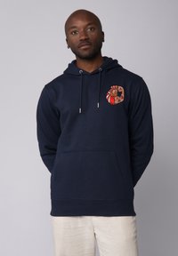 Hoodie bleu marine en tissu doux, avec un design graphique sur la poitrine gauche, une poche à l'avant et une capuche avec cordon de serrage réglable.