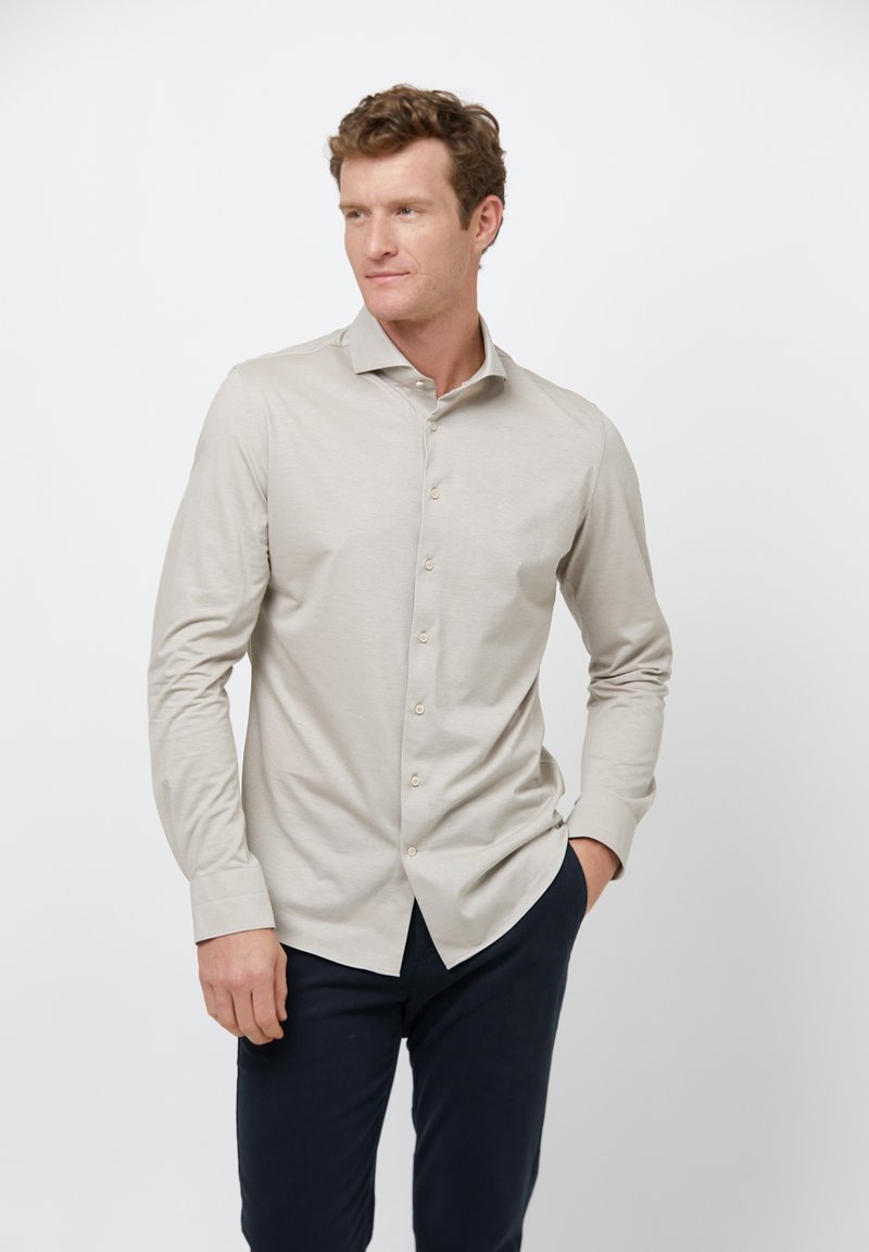 Lichtbeige langekraagshirt met een button-downkraag, met een gladde textuur en een subtiele glans, gecombineerd met donkerblauwe broek.
