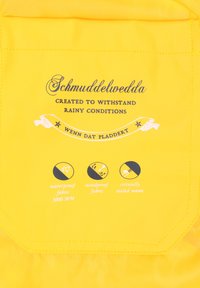 Gul vandtæt jakke med "Schmuddelwedda" branding, med ikoner der fremhæver vandtæt, vindtæt stof og kritisk forseglede sømme.