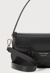 Czarna skórzana torba na ramię z plecionymi akcentami, srebrnymi elementami i regulowanym paskiem. Posiada tłoczone logo na skórzanej łatce.