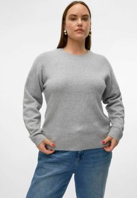 Pull en tricot gris avec un col rond, des poignets et un ourlet côtelés. Assorti avec un jean en denim bleu clair. Texture lisse, coupe décontractée.
