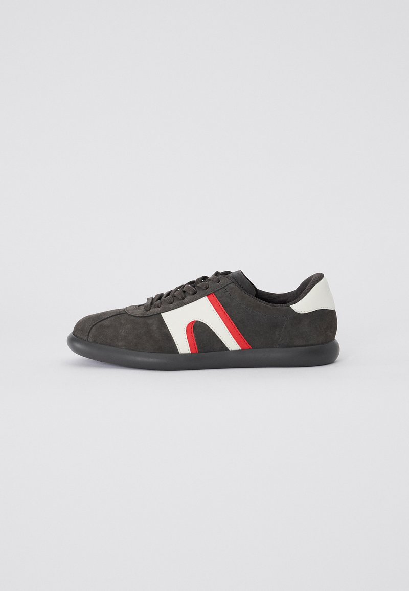 Sneaker con parte superiore in suede grigio scuro, accenti geometrici bianchi e rossi, suola in gomma nera e design della punta arrotondata.