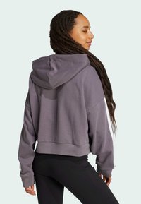 Lyhyt huppari pehmeästä harmaasta kankaasta, jossa on huppu, leveät hihat ja ribbireunat. Ominaisuuksiin kuuluu rento istuvuus ja minimalistinen muotoilu.